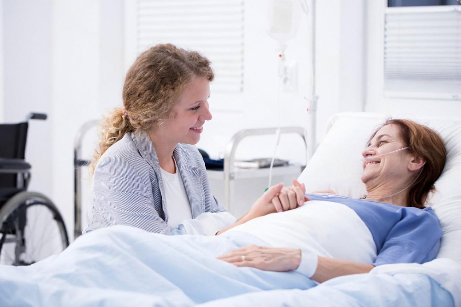 Patient recovering in hospital bed after gallbladder surgery, smiling with a visitor
